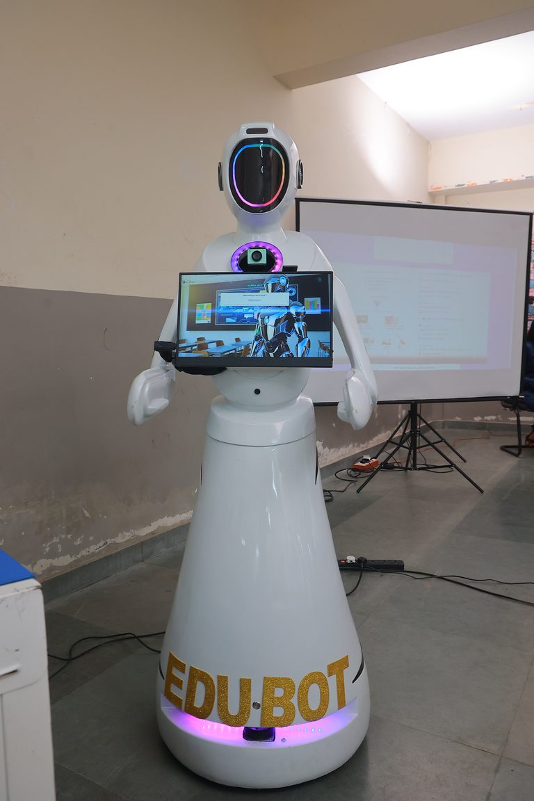 EDUBOT seen full height: a tapered white body with gold lettering, a chest-mounted touchscreen and a ring-lit camera head