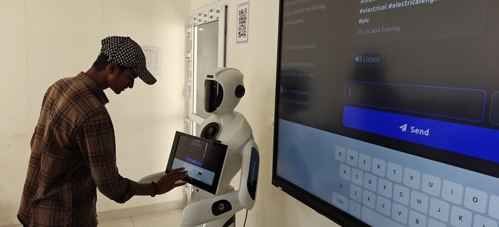 A trainee taps the robot's chest-mounted touchscreen. The wall display mirrors what the robot is showing: a PLC SCADA training topic, a Listen control, and a box for typing a question