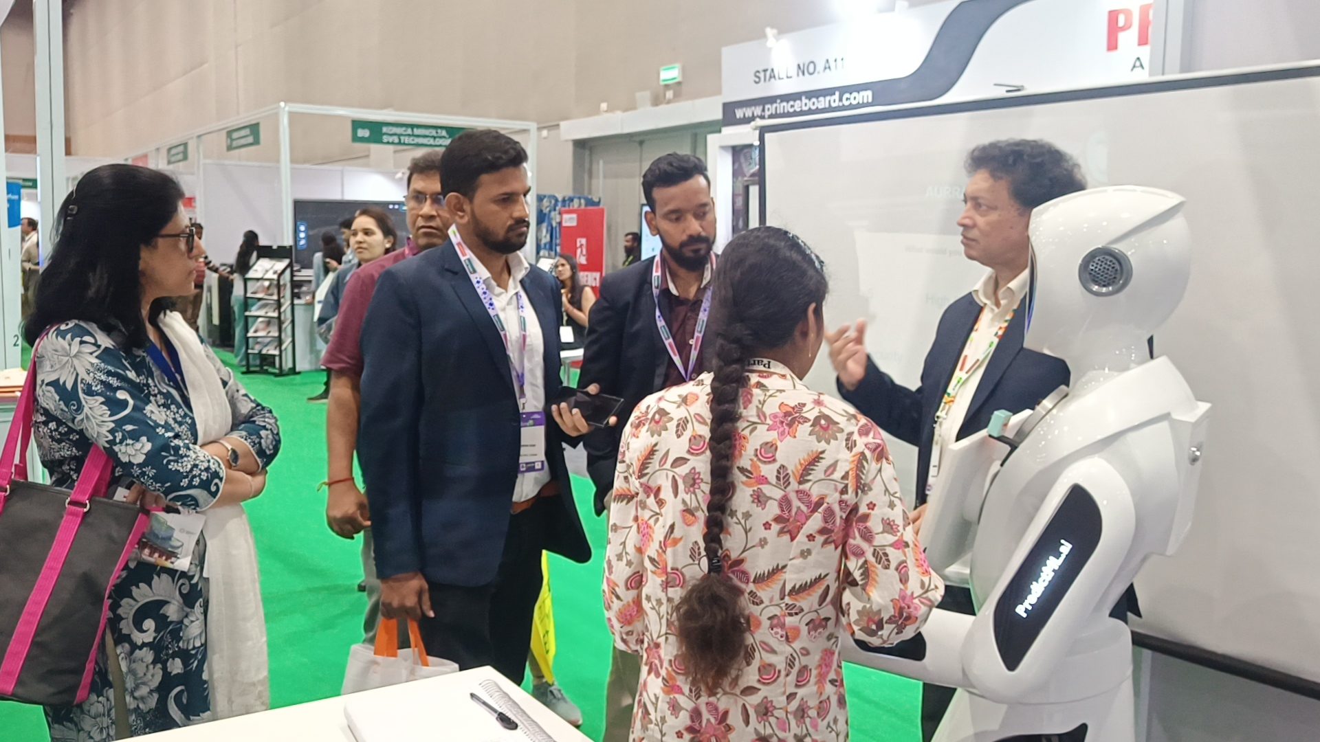 Visitors in conversation beside the robot at a trade exhibition stand