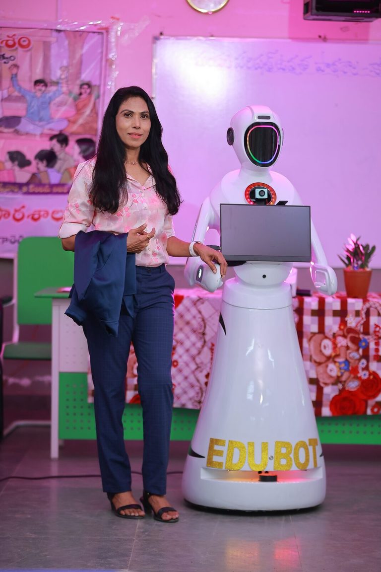 A PredictML presenter standing with EDU-BOT on a school stage