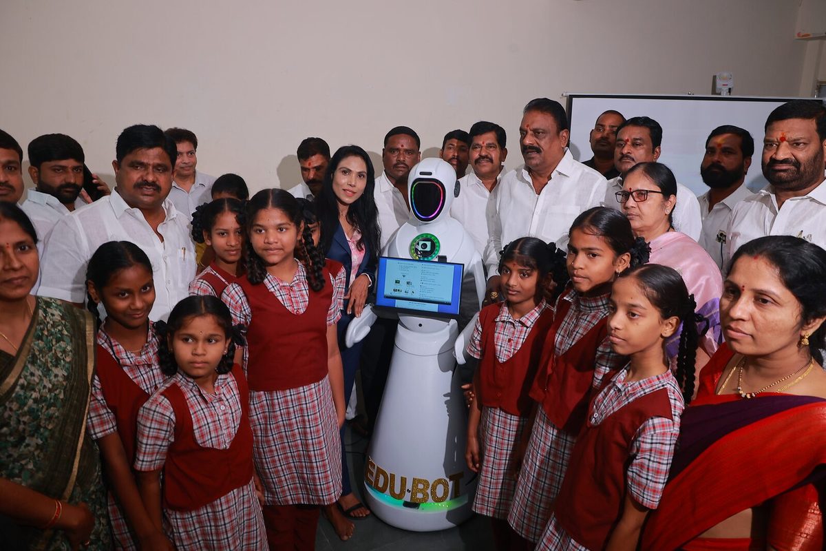 Students in school uniform standing either side of EDU-BOT, its screen turned toward them
