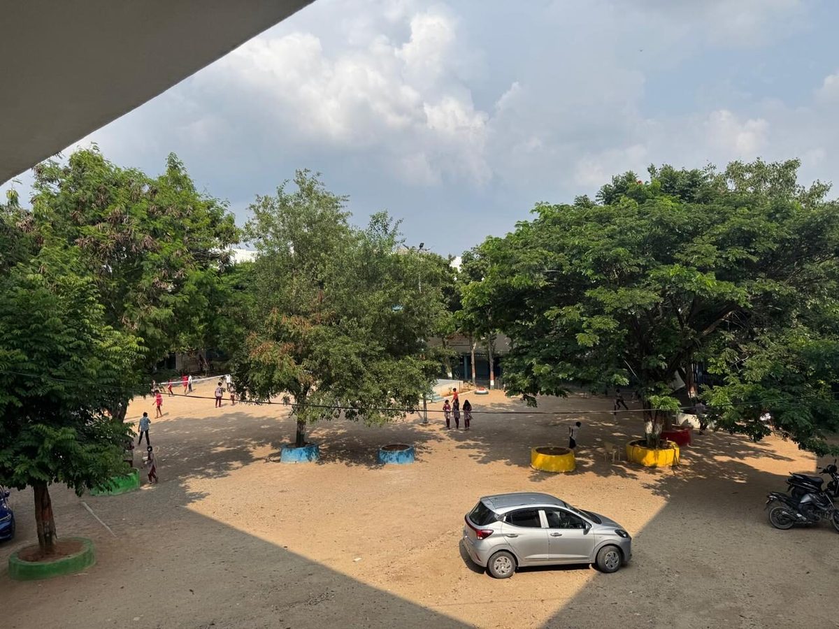 The school yard at Narsingi, with trees and students crossing the ground